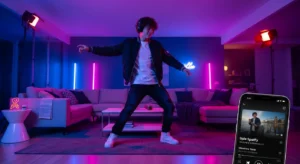 Homem jovem dançando animado em uma sala iluminada com luzes de LED roxas e azuis, ouvindo música pelo celular conectado a um aplicativo de streaming, transmitindo uma atmosfera divertida e moderna de festa em casa.